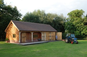 This four-bay SuperSize building (frame SS-K50) was modified in height to allow access for commercial storage of large scale farm equipment. The two front recessed bays create a pleasing porch area, housing an oak stable door.