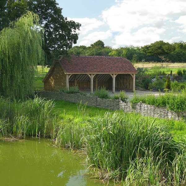 This open-fronted three-bay barn is clad in oak. The lifespan of oak cladding is greater than softwood timber cladding, but the oak does not perform as well due to shrinkage and splitting. However, with age, it does add more character to the building.